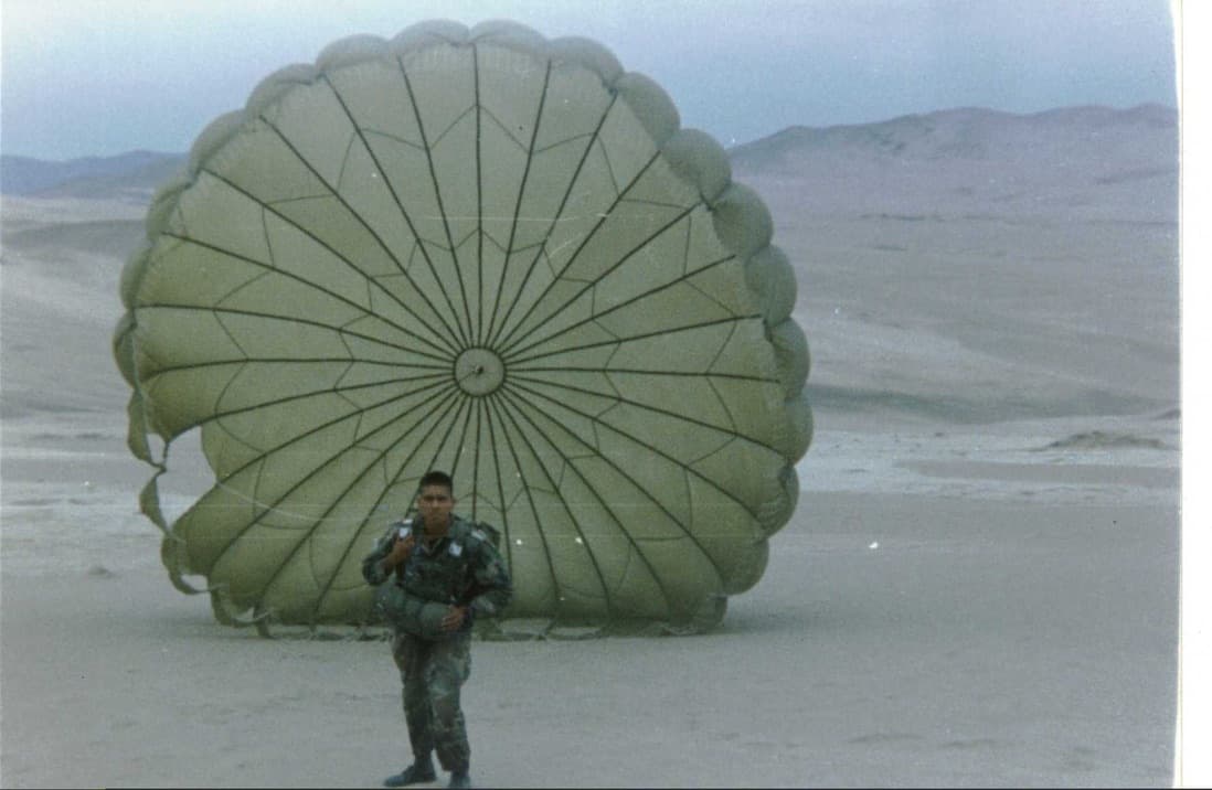 Jorge during his Peruvian Army years, standing in front of an open parachute